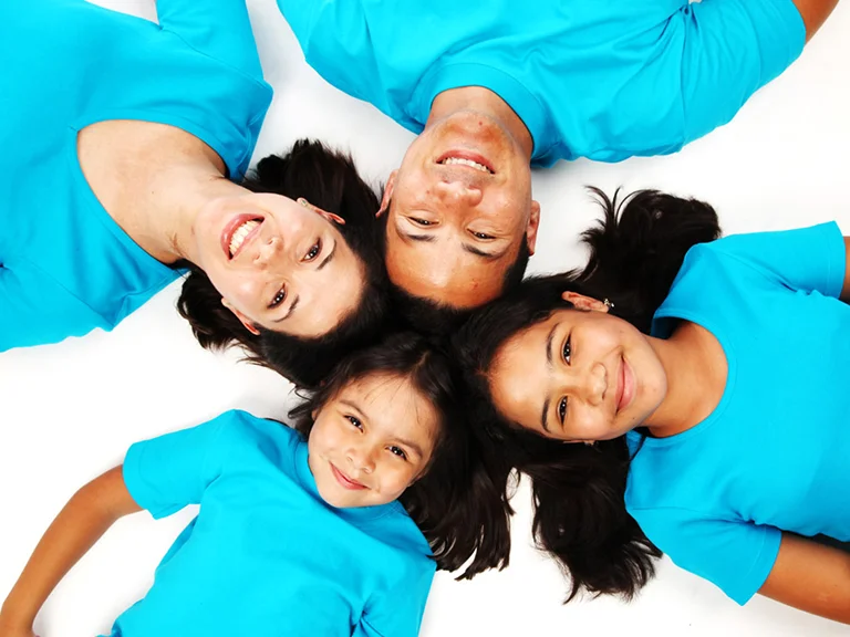 Famille de quatre personnes en t-shirts turquoise, allongée tête contre tête, photo de famille en studio à Genève