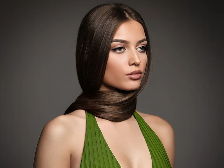 Book Mannequin : portrait beauté d’une femme aux longs cheveux bruns en robe verte, sur fond gris