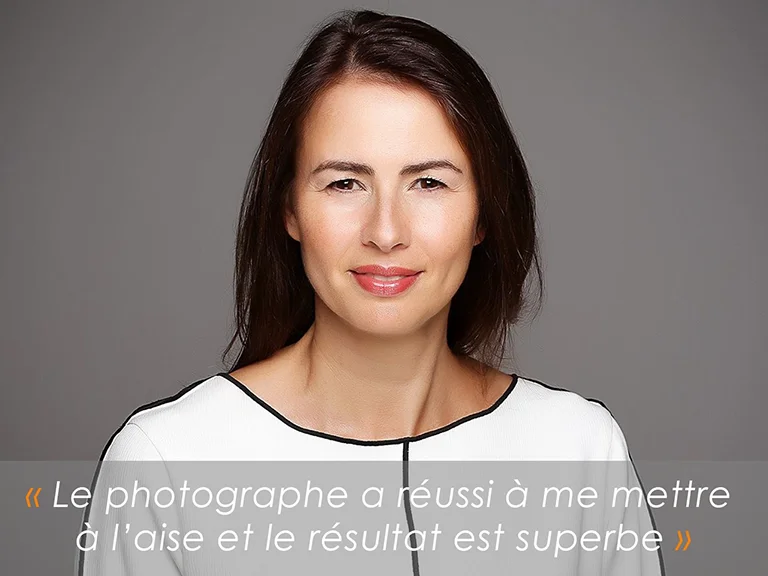Portrait CV-LinkedIn : femme souriante en haut blanc sur fond gris, photographiée en studio à Genève